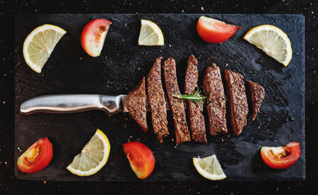 Grilled beef steak, Tenderloin on black stone plate with tomato and lemonの写真素材
