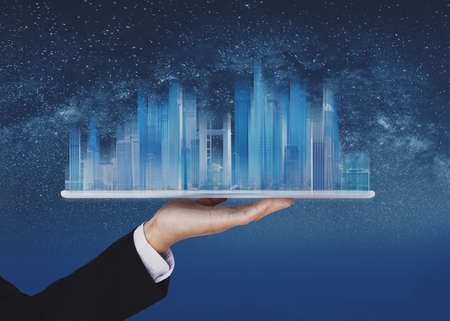 Businessman holding blue modern buildings hologram on handの写真素材
