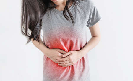 Stomach aches and Monthly period pain. Young woman holding stomach with red highlightの写真素材