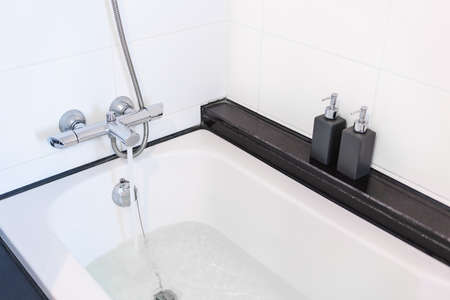 Close-up bath tub with opening water from faucetの写真素材
