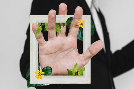Businessman hand with picture frame, and flowers with leaves. Digital collage modern artの写真素材