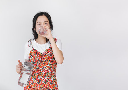 Healthy beautiful young Asian woman, drinking water, on white backgroundの写真素材