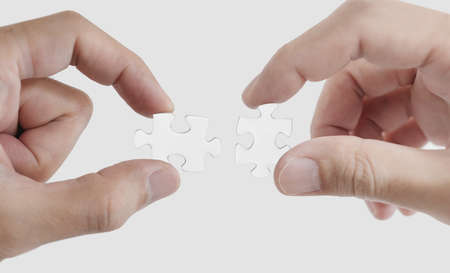 Close-up hands connecting jigsaw puzzle, isolated on white background