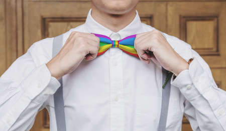 Close-up a man tying rainbow bow tieの写真素材