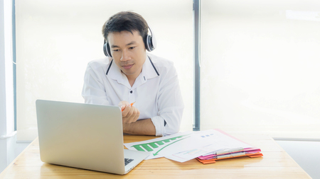 Businessman wearing headphones singing song and using laptop during break in the office.の写真素材