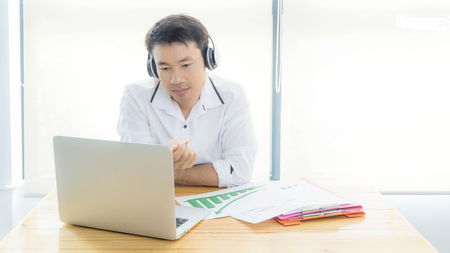 Businessman wearing headphones singing song and using laptop during break in the office.の写真素材