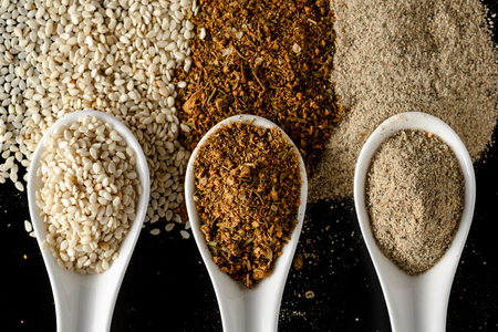 three porcelain spoons with spices on a black background isolated. Top viewの写真素材