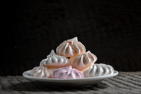 Multicolored meringue in a plate on a black backgroundの写真素材