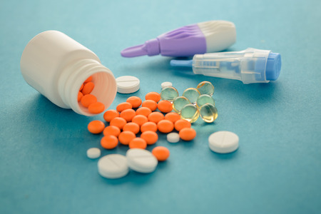 a composition of tablets of different kinds and lancets, adults and children on a blue background....