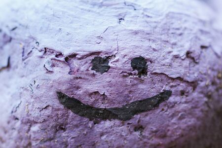A colored stone with a painted smiley. Close-up. Decoration from a stoneの写真素材