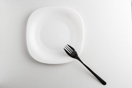 empty white plate and fork on a white background. View from aboveの写真素材
