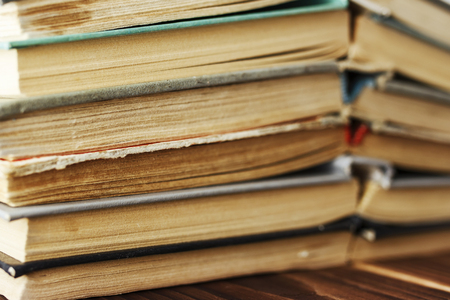 A stack of old books on a wooden table. Toned photoの写真素材