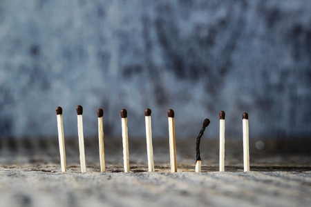 The matches stand in a row on a gray background, one match burned out. The concept of loss. Place for textの写真素材