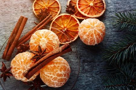 Juicy tangerine mandarins without peel lie on a plate with anise and chopsticks and fir branches lies on wooden tableの写真素材