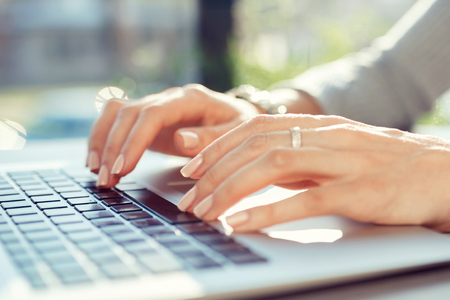 The girl at the table in the cafe picks up the text on the laptop keyboard. Workplace conceptの写真素材