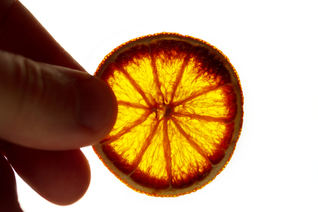 orange on white background isolate. The hand holds a piece of dried orangeの写真素材