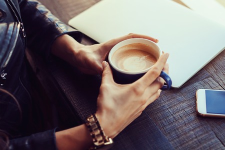 hands of the girl holding a cup of coffee on the background of aの写真素材