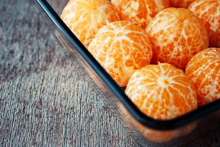 mandarines without peel lie in a plate on a wooden background. Photo with copy spaceの写真素材