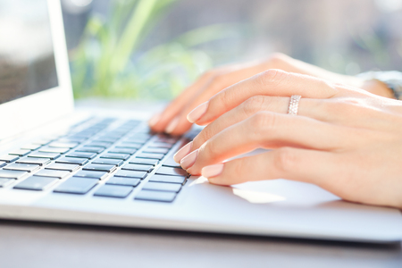 young woman working on laptop in cafe on bright sunny dayの写真素材