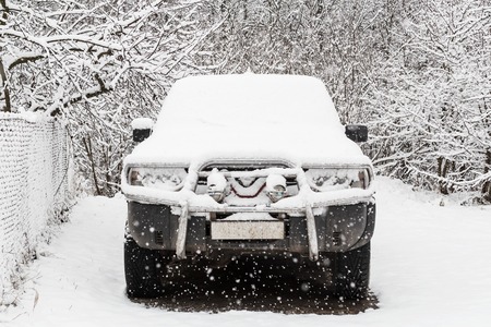 old SUV covered with first snow. car buried under the snow and frozenの写真素材