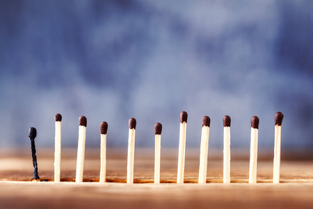 a row of matches on a wooden background, the last match burned down. Extinct match next to unlitの写真素材