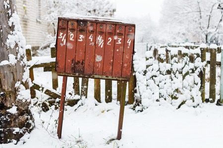 old rickety mailbox in the winter under the snow. Mailbox with written figures and peeling paintの写真素材