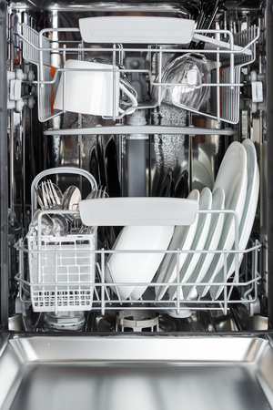 open dishwasher front view. Clean plates, cups, glasses and cutlery in the dishwasher after washingの写真素材