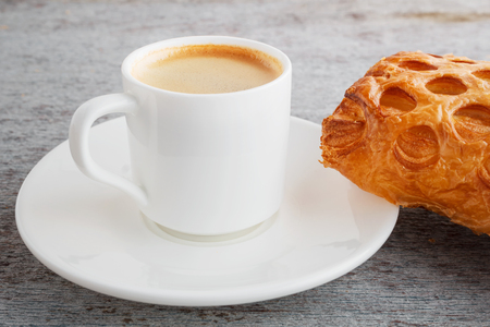 a fragrant cup of freshly brewed coffee and a croissant on a wooden backgroundの写真素材