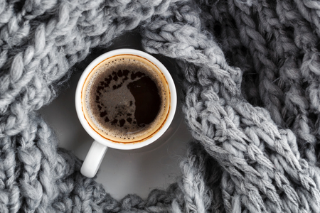a cup of coffee wrapped in a woolen warm gray scarf. Top viewの写真素材