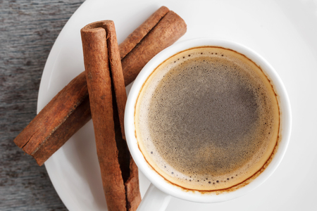 a cup of fragrant coffee and cinnamon sticks on a gray wooden background close-up. Top viewの写真素材