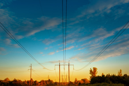 high - voltage power line. Wires and power towers of electricity above the forest at sunset. Supply of energyの写真素材