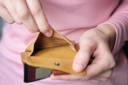 empty wallet in the hands of a young woman in a pink sweater. The concept of poverty, insolvencyの写真素材