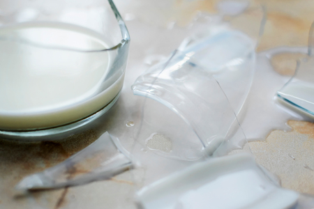 fragments of a broken jug and poured milk on a tableの写真素材