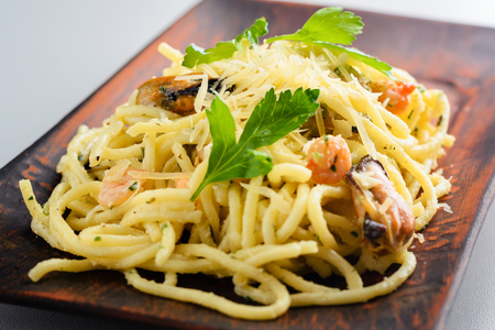 homemade pasta with seafood, mussels and shrimps, sprinkled with parsley leaves and grated Parmesan cheese. Traditional Italian cuisineの写真素材