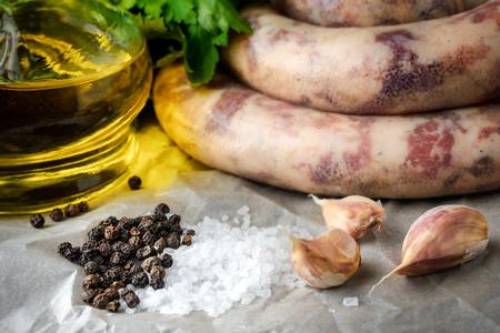 Homemade sausages, spices, garlic, parsley and olive oil on the table.の写真素材
