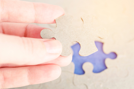 The missing part of the puzzle in the girl's hand. Toned photoの写真素材