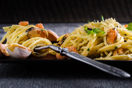Pasta with seafood shrimps and mussels in creamy sauce on a plate on a dark backgroundの写真素材