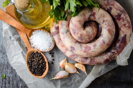 Homemade sausages, spices, garlic, olive oil and parsley on a wooden table. Top viewの写真素材
