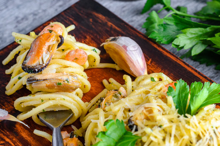 Pasta with seafood mussels and shrimps in a creamy sauce and a bunch of parsley on a plate.の写真素材