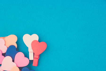 Loving couple of wooden hearts in the center surrounded by colored hearts on a blue background with copy spaceの写真素材