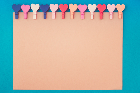 paper for notes hanging on wooden colored hearts on a blue backgroundの写真素材