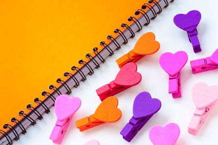 yellow paper and small colored wooden hearts on a white background. Concept notes for Valentine's Dayの写真素材