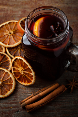 homemade mulled wine, dried oranges and cinnamon sticks on a wooden table on a dark background. Top viewの写真素材