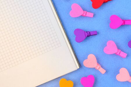 White paper and small wooden colored hearts on a blue background. Concept notes for Valentine's Dayの写真素材