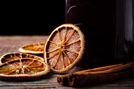homemade mulled wine, dried oranges and cinnamon sticks on a wooden table on a dark background. Close upの写真素材