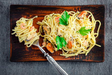 Pasta spaghetti with seafood in a creamy sauce on a wooden table in rustic style. Mediterranean Italian cuisine. top viewの写真素材