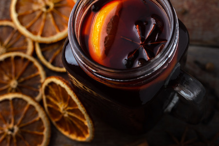 glass cup with mulled wine with dried oranges and spices on a wooden table in rustic style.の写真素材