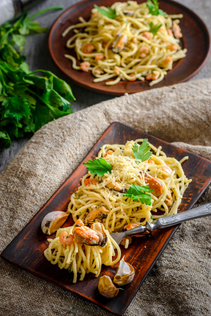 talian pasta in a creamy sauce with seafood, shrimps and mussels on a plate on a dark wooden background. Vertical compositionの写真素材