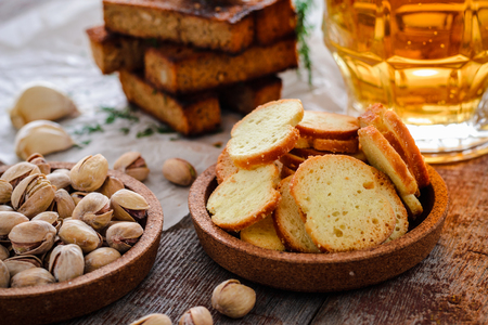 Beer in a glass, pistachios, rye croutons with dill and crackers on a wooden tableの写真素材
