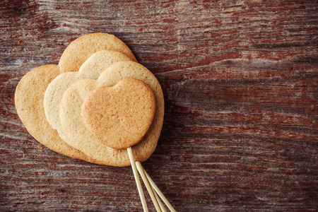 Ginger cookies on a stick in the form of hearts on a wooden background. Top view with copy spaceの写真素材